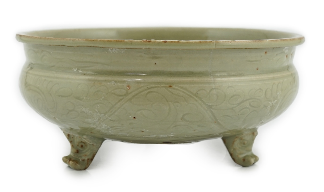 A Chinese Ming Longquan celadon tripod censer, 14th/15th century, the exterior incised with scrolling foliage, on three animal mask feet, burnt orange ring to base, 26.7cm diameter, original receipt for Wing Kei curios,